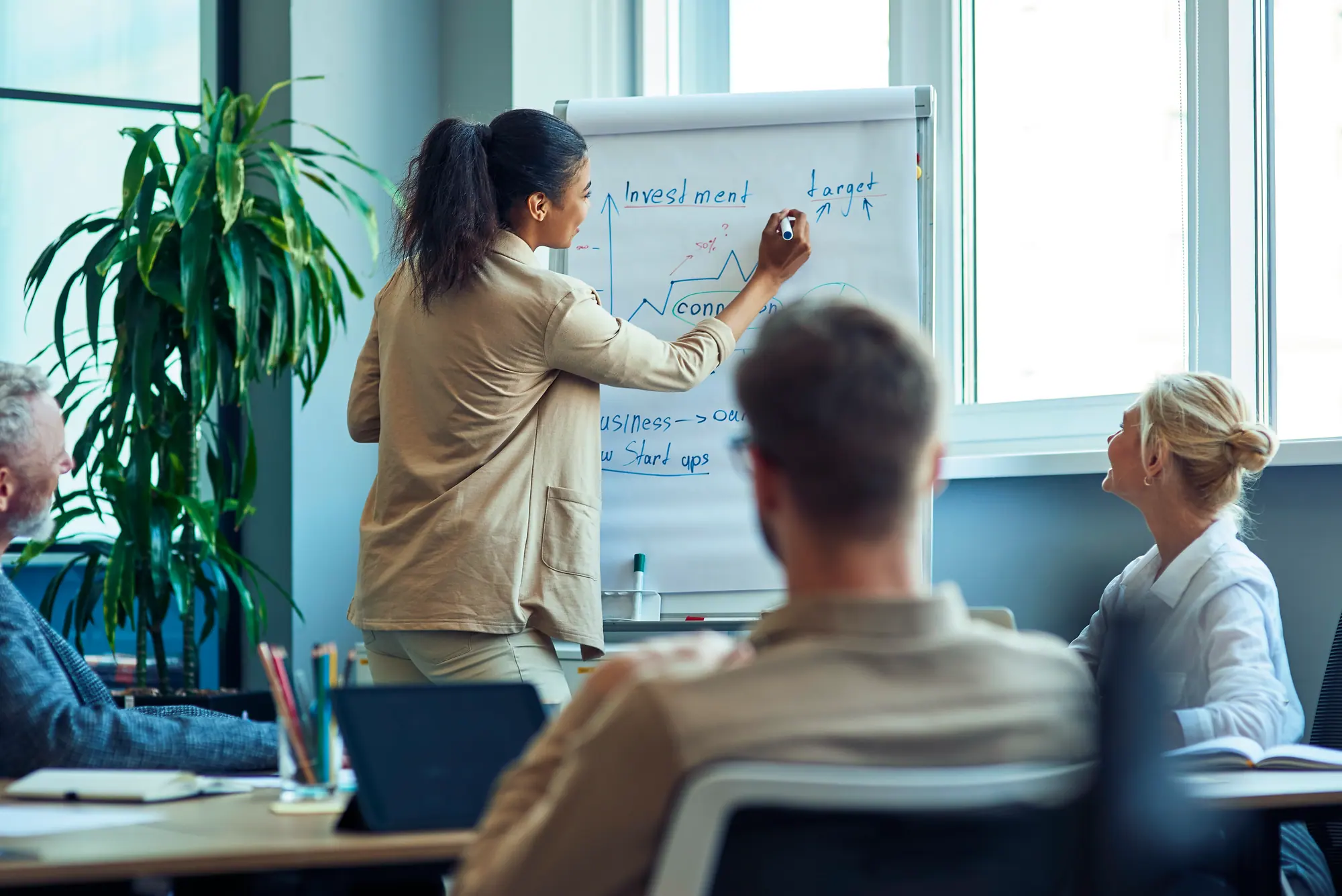 Une formatrice explique un schéma sur un tableau à deux apprenants