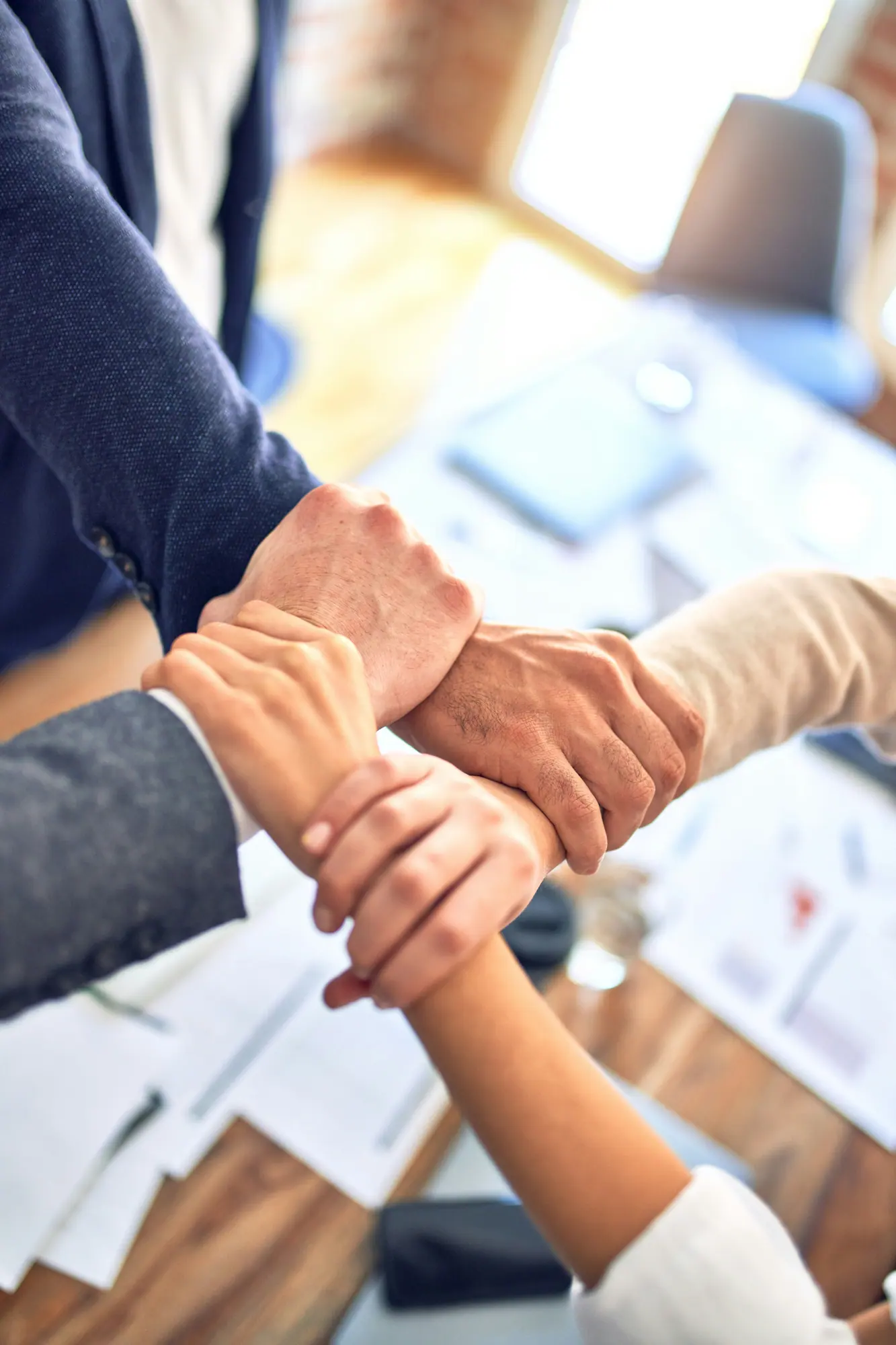 Plusieurs mains se rejoignent au centre d'une table de travail