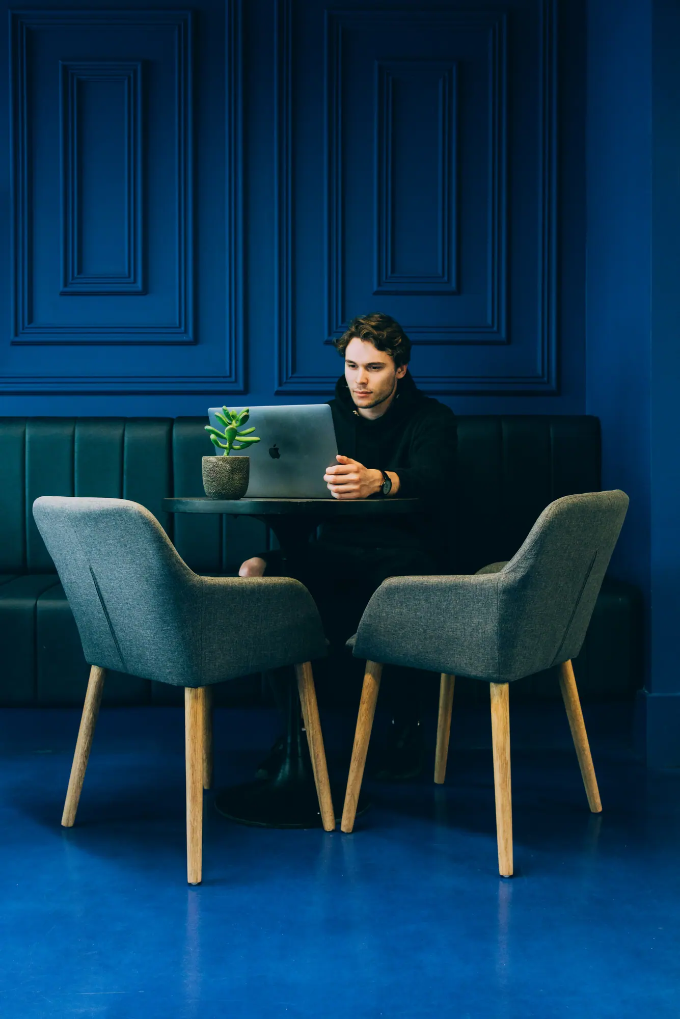 Un homme travaille sur un ordinateur portable devant un mur bleu