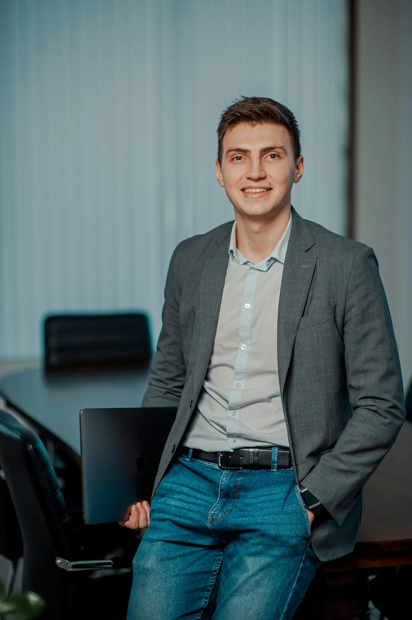 Un professionnel en veste grise, debout dans un bureau